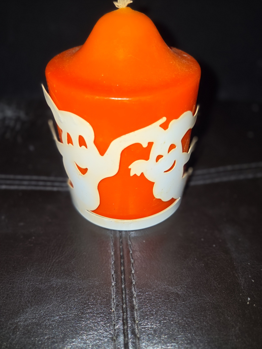 Source Unknown Orange Pillar Candle with White Ghost Silhouette.